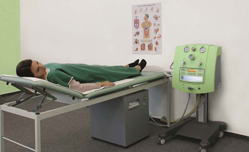 Patient lying next to to a Colon Hydrotherapy Machine
